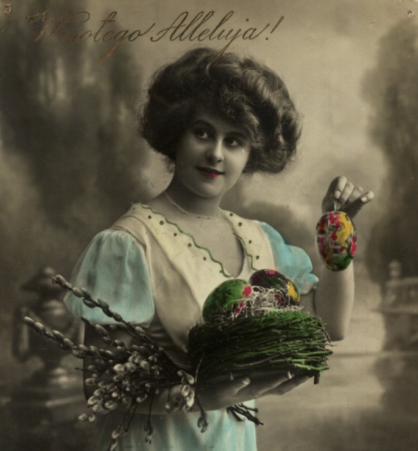 Stara pocztówka przedstawiająca uśmiechniętą kobietę trzymającą koszyk pisanek, u góry napis Wesołego Alleluja!
