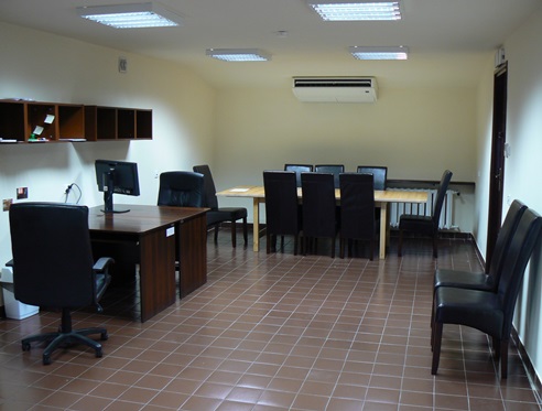 Wnętrze Pracowni Projektów Badawczych. Po lewej biurka z fotelami, po prawej dwa krzesła, na dalszym planie duży stół.